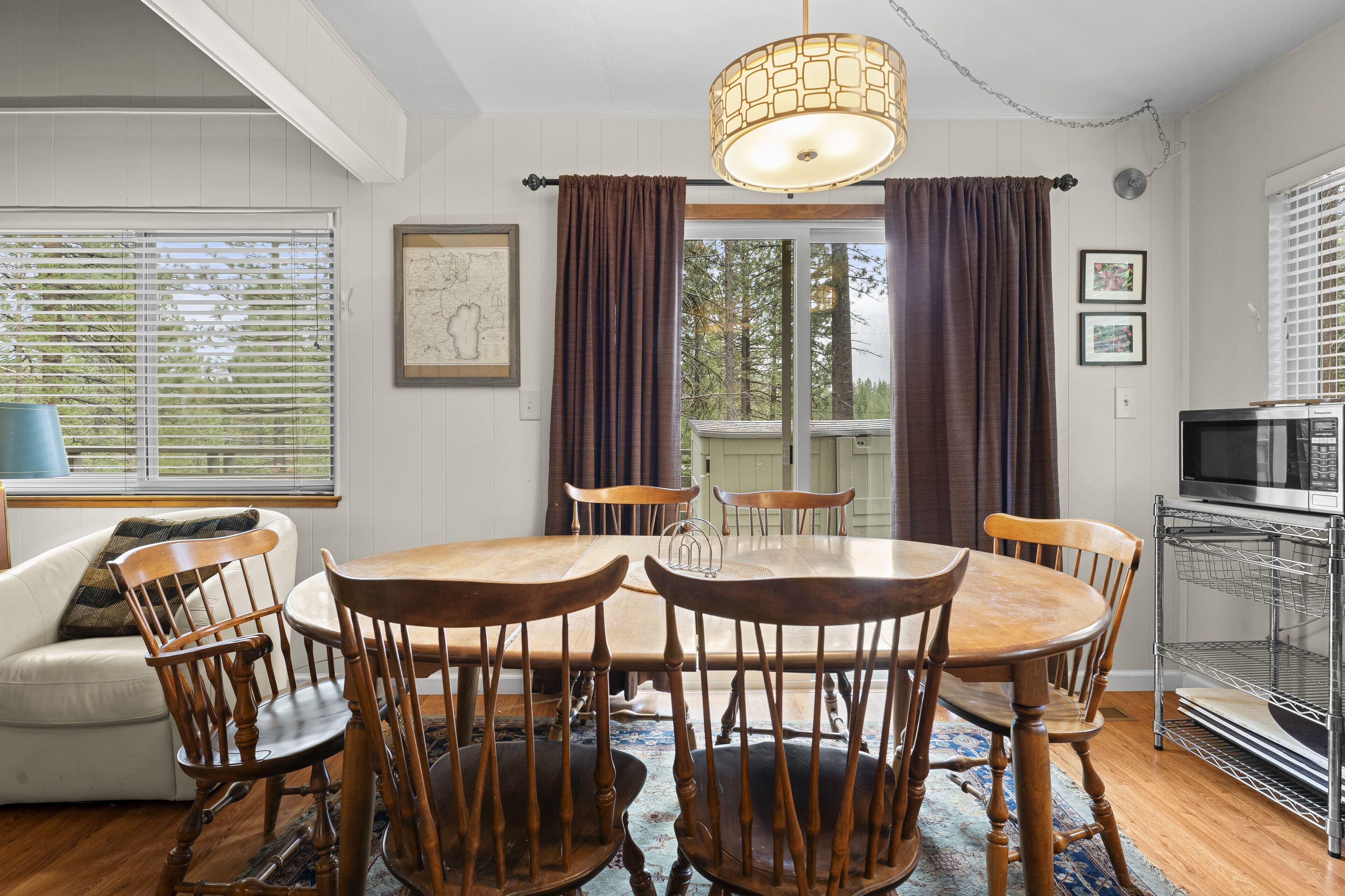 A dining area with a wooden table and chairs, a white sofa, and a blue lamp.