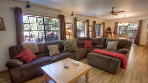 A cozy living room with a brown sofa set, a wooden coffee table, and large windows with curtains. - Bear Country 4 Bedroom Home by RedAwning (South Lake Tahoe)