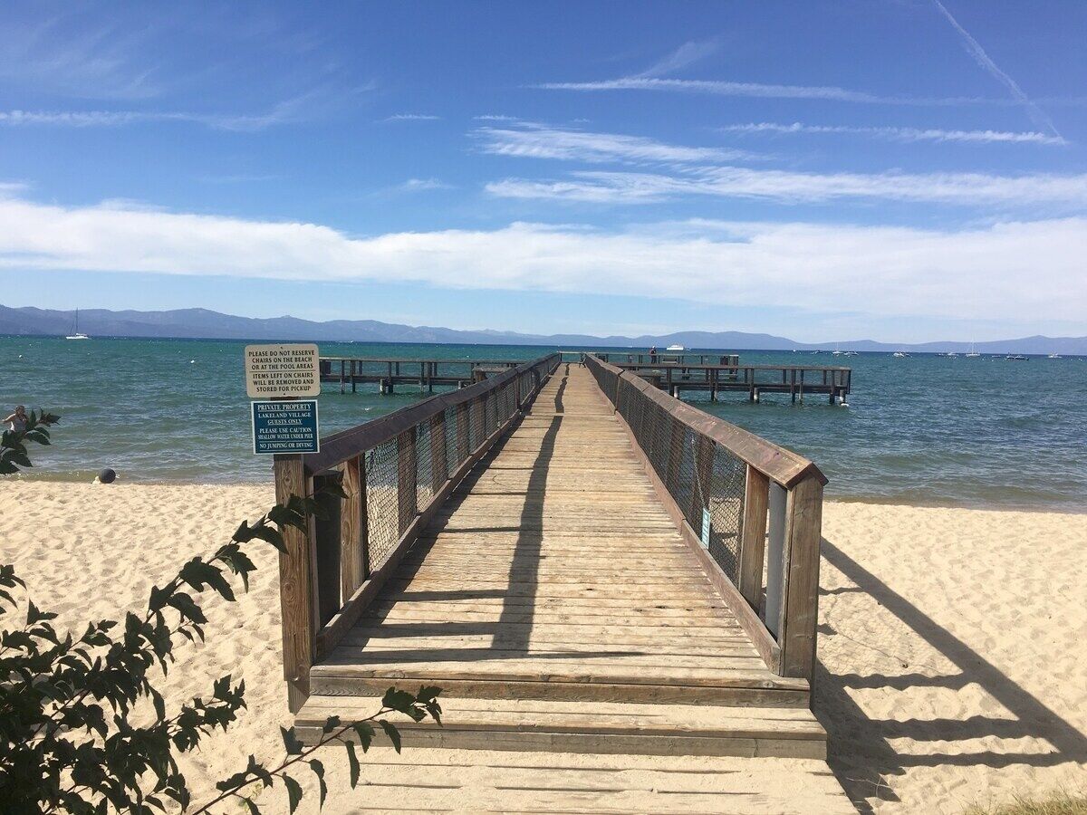 A wooden pier leading to a beach with a sign indicating no parking or stopping on the pier.
