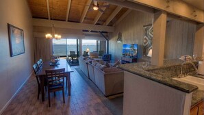 A spacious living area with a wooden ceiling, a dining table with chairs, a sofa, and a kitchen area with a sink and countertop. - Sky Lake Splendor 5 Bedroom Condo by RedAwning (South Lake Tahoe)