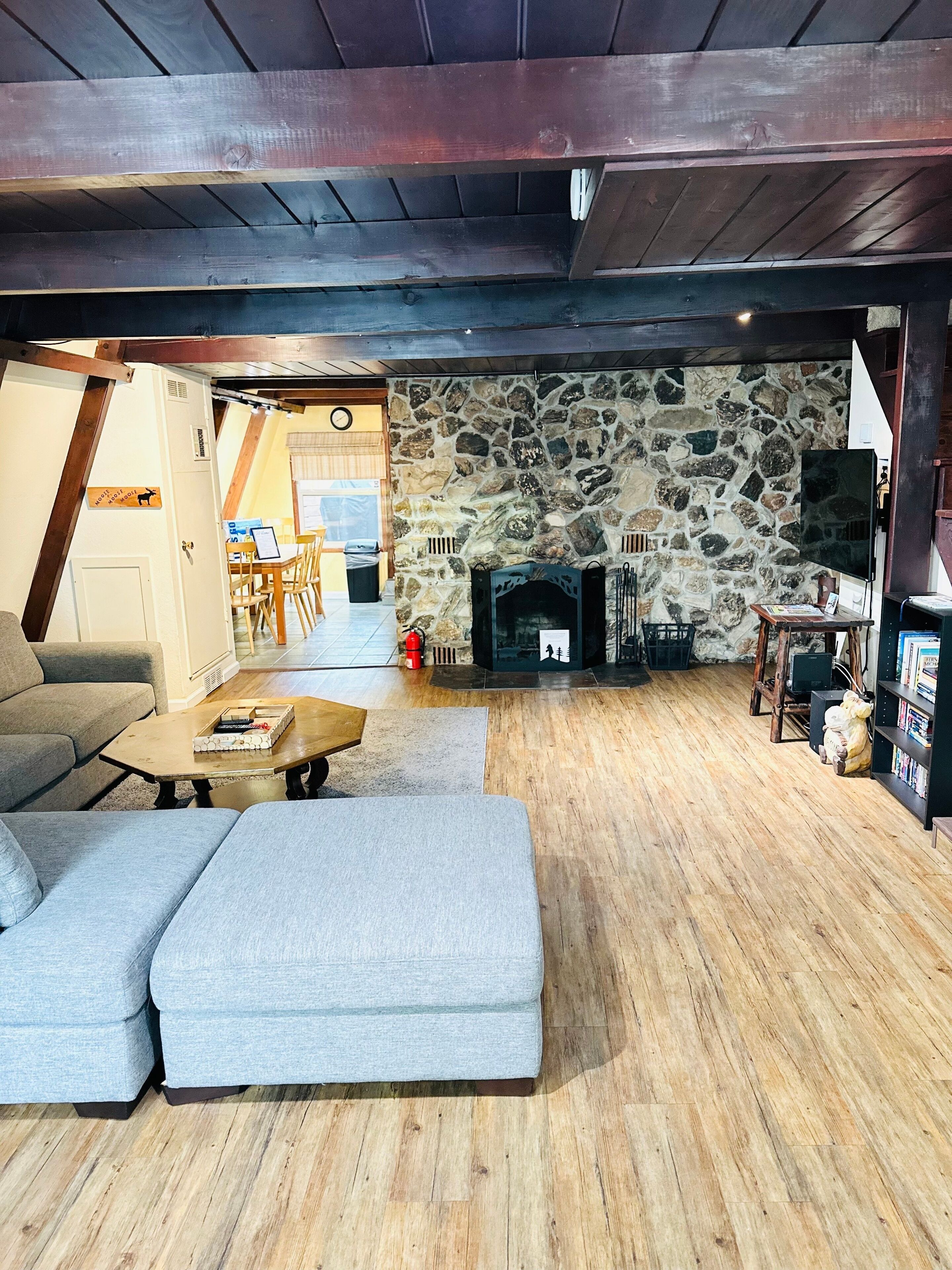 A cozy living room with a stone fireplace, wooden flooring, and a modern sofa.