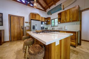 Une cuisine avec des meubles en bois, un grand îlot central et un ventilateur de plafond.