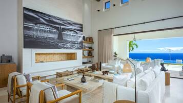 Relax in style with a view of the ocean from this elegantly furnished living area, featuring a nautical-themed photograph and comfortable seating.