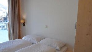 A room with two beds, a wooden door, and a window with curtains.
