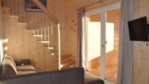 A wooden interior with a sofa, a staircase, and a television.