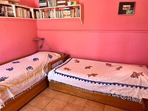 Two single beds with patterned bedding, a bookshelf with books, and a framed picture on the wall. - Villa in the countryside in a wooded property (Ile de Porquerolles)