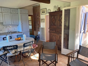 A kitchen with a dining table, chairs, and a refrigerator. - Villa in the countryside in a wooded property (Ile de Porquerolles)