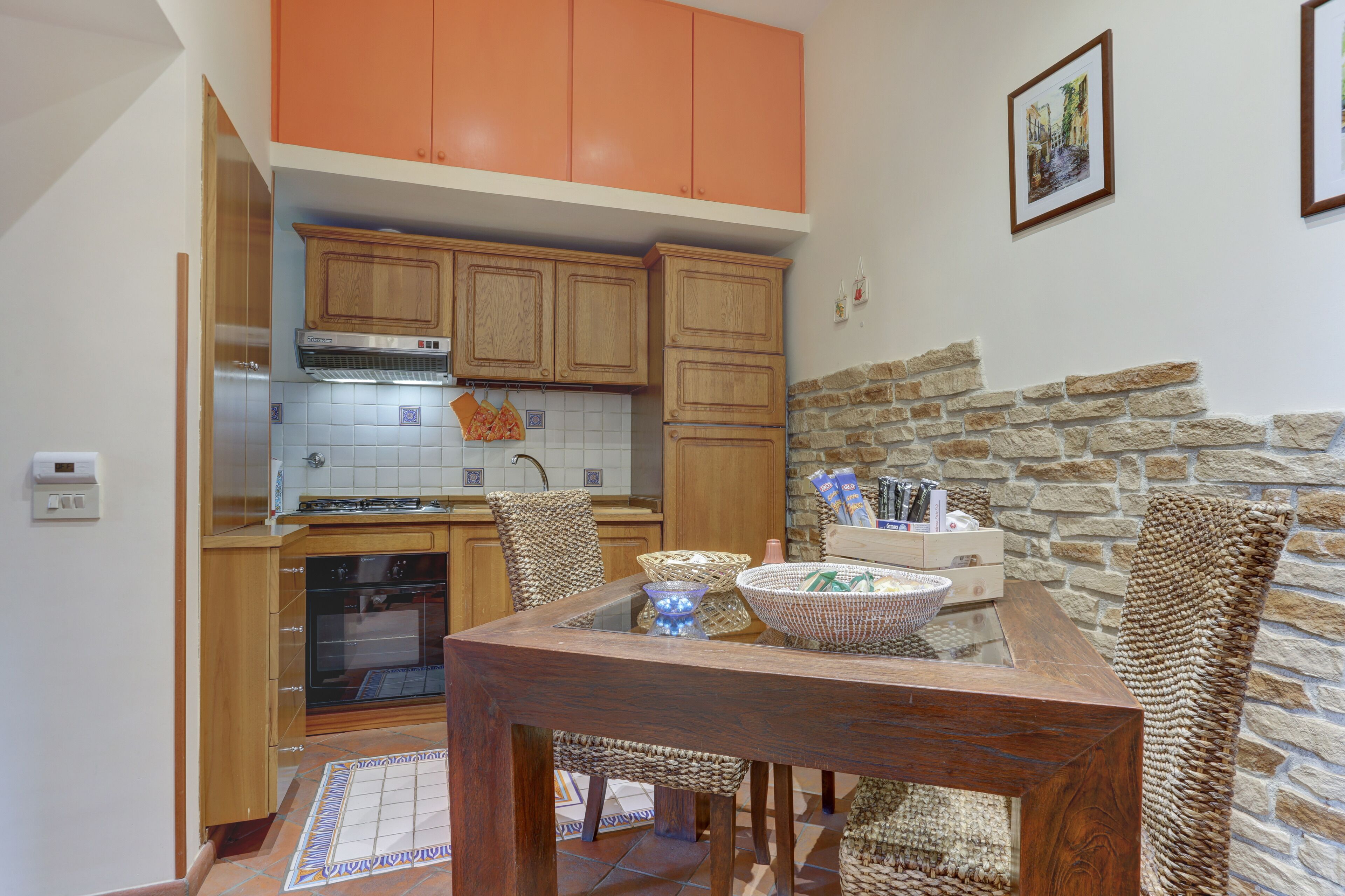 Una cocina con armarios de madera, una pared de piedra y un comedor con sillas de mimbre.
