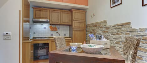 Una cocina con armarios de madera, una pared de piedra y un comedor con sillas de mimbre.