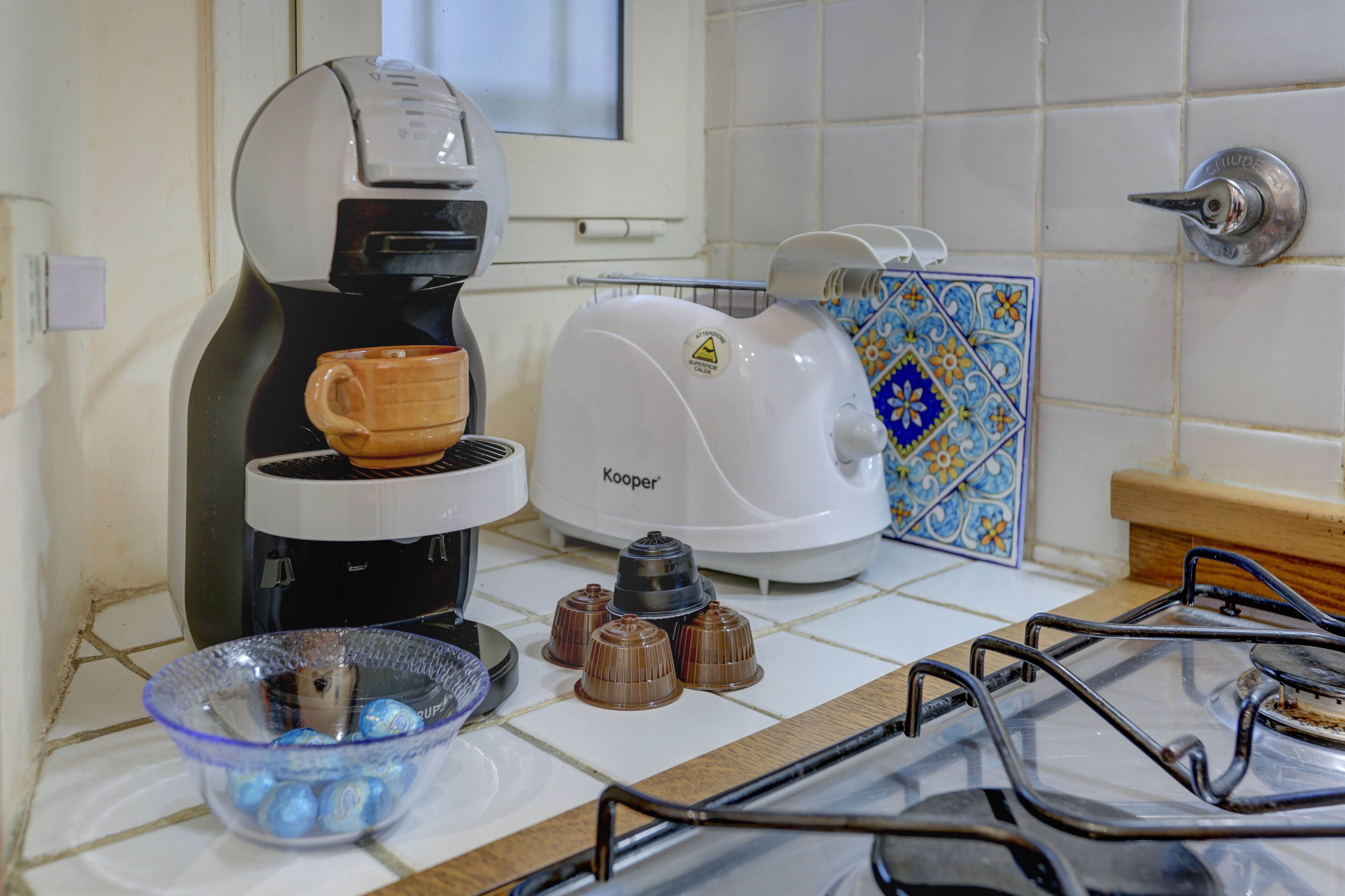 A kitchen with a coffee maker, toaster, and a bowl of chocolates on the counter.