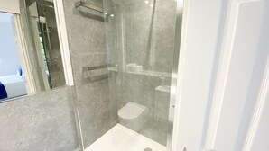 Un baño moderno con ducha acristalada, inodoro y lavabo.