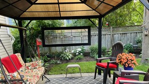 A covered patio area with a patterned rug, outdoor furniture, and a wooden fence in the background. - Walk to Victoria Hospital - fenced yard - quiet neighbourhood (London)