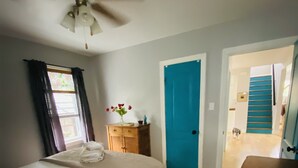 A bedroom with a bed, a wooden dresser, a blue door, and a staircase leading to another room. - Walk to Victoria Hospital - fenced yard - quiet neighbourhood (London)