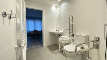 A modern bathroom with a toilet, bidet, sink, and a mirror.