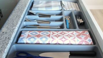 A kitchen drawer with utensils, a knife, and a pair of scissors.