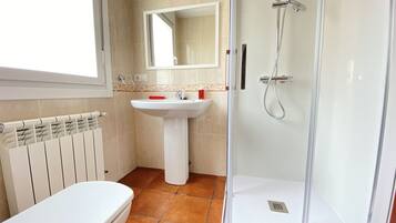 Een badkamer met toilet, wastafel en douche.