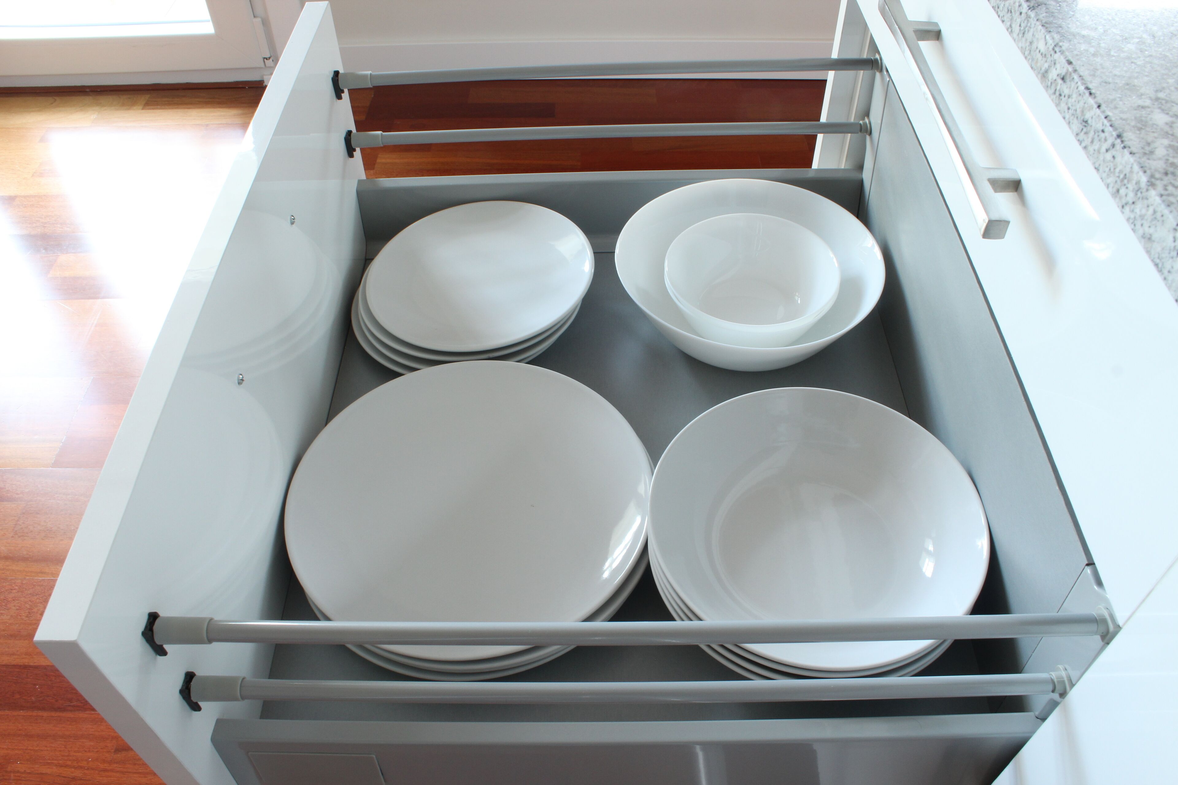 Un cajón con platos y cuencos blancos.