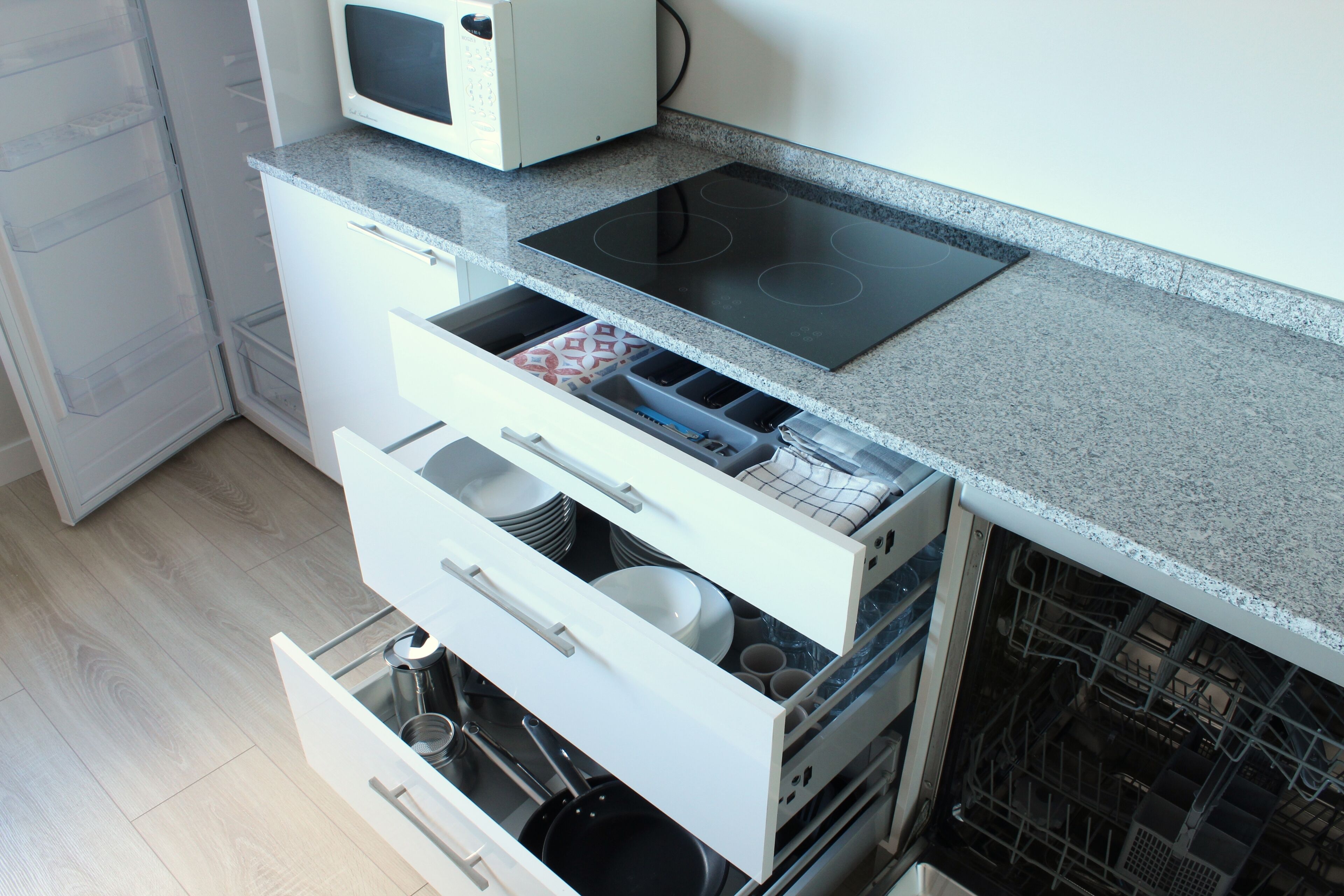 Een keuken met een magnetron, kookplaat en diverse lades en kastjes.