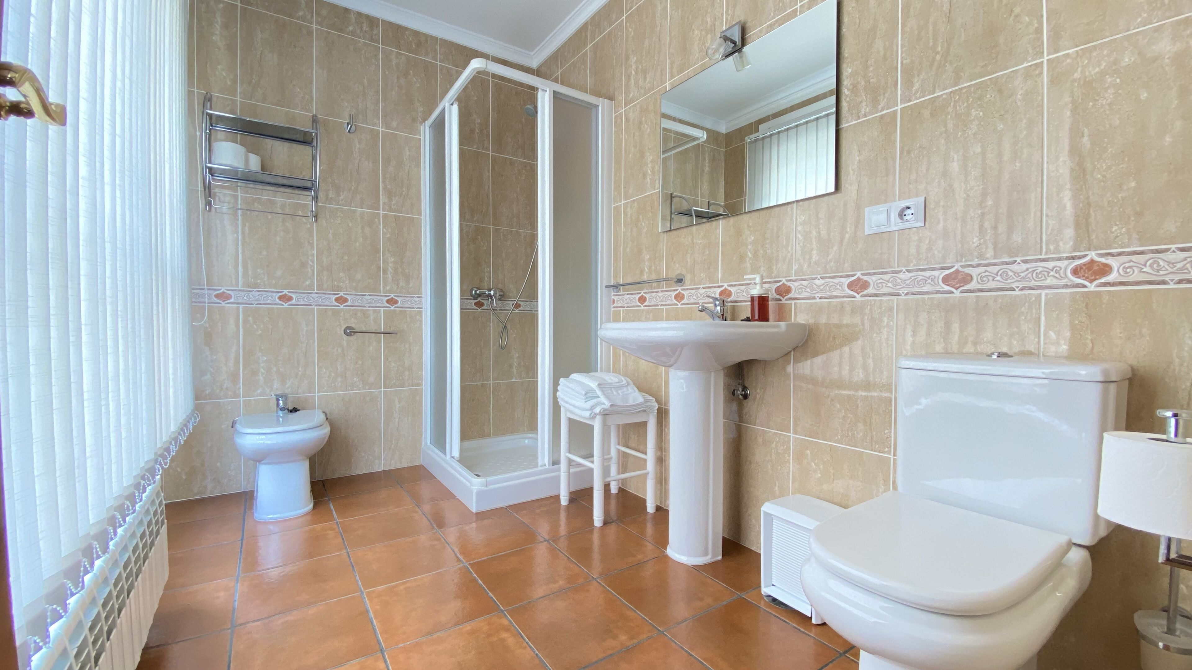 Een badkamer met toilet, wastafel, bidet en douche.
