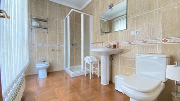 Een badkamer met toilet, wastafel, bidet en douche.