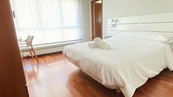A hotel room with a large bed, a chair, and a window with blinds.