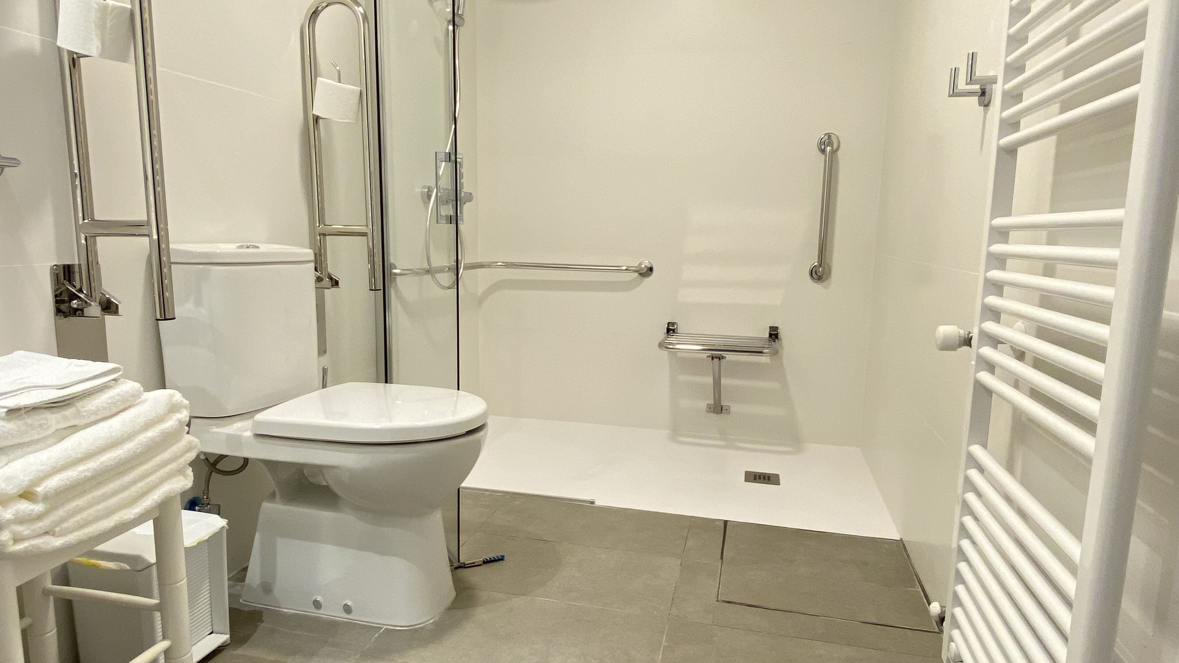 Une salle de bain moderne équipée de toilettes, d’une douche et d’un porte-serviettes.