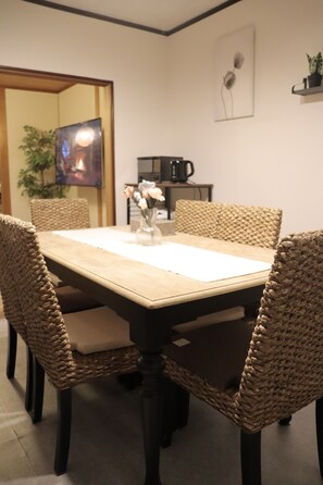 A dining area with a rectangular table, woven chairs, and a vase with flowers.