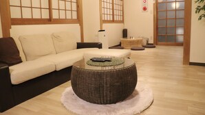 A traditional Japanese-style living room with a sofa, a round wicker coffee table, and a tatami mat. - 2-minute walk from Tenjinbashisuji Rokuchome Station! A house with a rooftop terrace 2 min. from Tenma Izakaya district 10 min. from Umeda 15 min. from Namba Max. 13 persons (大阪市北区)