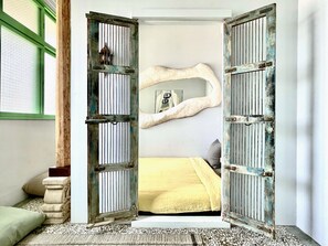 Un dormitorio con cama, espejo y un par de puertas abiertas.