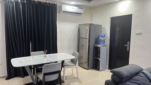 Un espacio habitable compacto con una mesa de comedor, sillas, un sofá, un refrigerador, un dispensador de agua y una puerta.