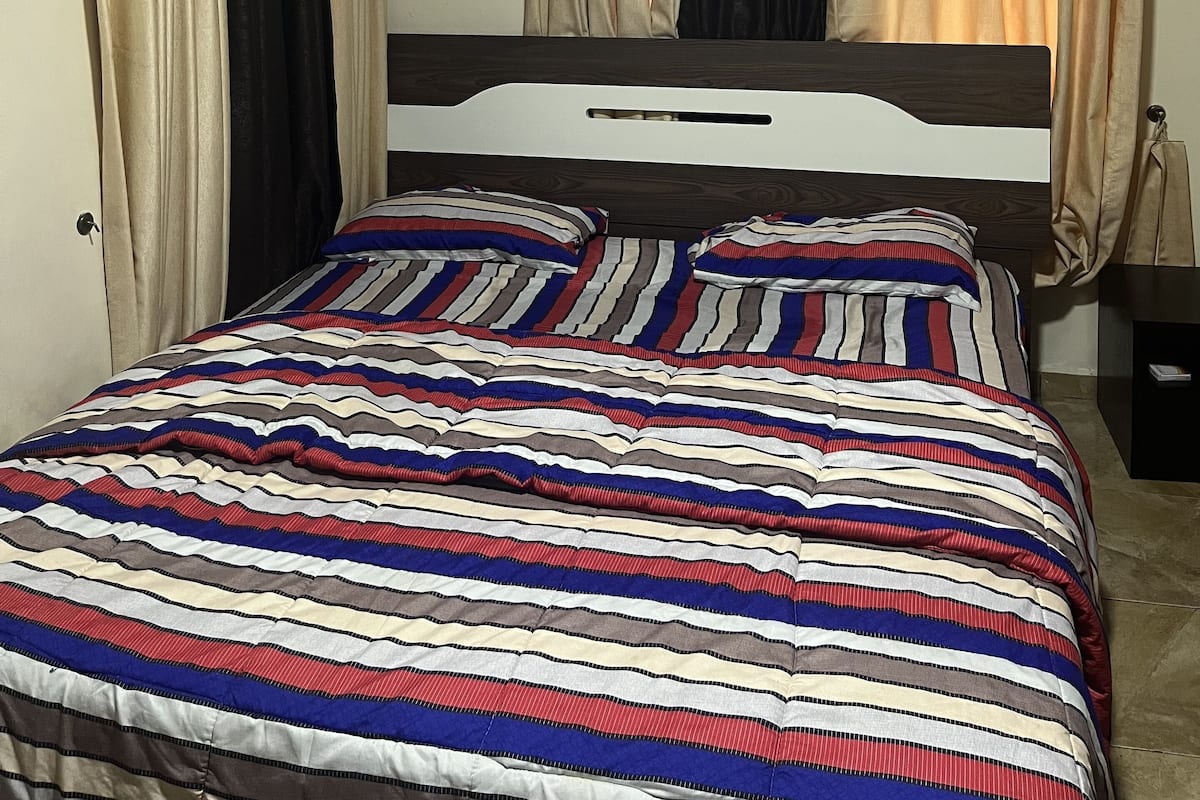 A bedroom with a bed, curtains, and an air conditioning unit.