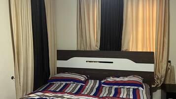 Un dormitorio con cama, cortinas y un equipo de aire acondicionado.