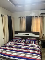 Un dormitorio con cama, cortinas y un equipo de aire acondicionado.