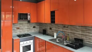Una cocina con gabinetes naranja, un microondas, una estufa a gas y un fregadero.