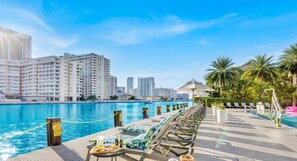 Relax by the pool with a view of the city skyline, surrounded by lounge chairs and a dining area.