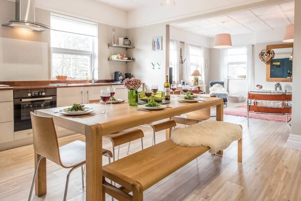 Une cuisine moderne avec des plans de travail en bois, une table à manger pour quatre personnes et un banc.