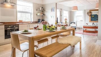 Une cuisine moderne avec des plans de travail en bois, une table à manger pour quatre personnes et un banc.