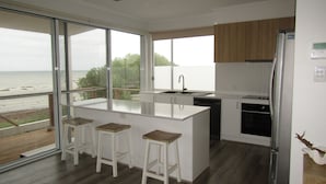 Une cuisine moderne dotée d’un grand îlot central, de tabourets de bar, d’un lave-vaisselle et d’un réfrigérateur.