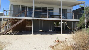 Une maison moderne à deux étages, dotée d’un balcon, d’une balançoire et d’un espace extérieur couvert.