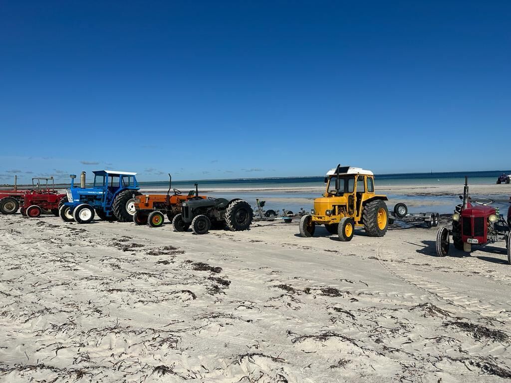 Een zandstrand met verschillende tractoren er op.