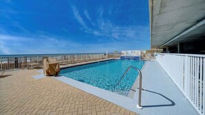 Zona de piscina con vista despejada al océano, un puesto de socorristas y una sección cubierta.