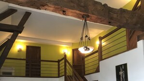A multi-level interior with a wooden staircase, a dining area, and a staircase with a yellow railing.