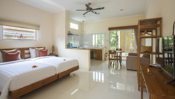 A spacious bedroom with a large bed, a desk, and a dining area. - Donguri House Bali (Kedonganan)