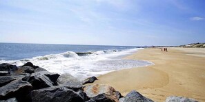 A beach with waves, rocks, and a clear sky.