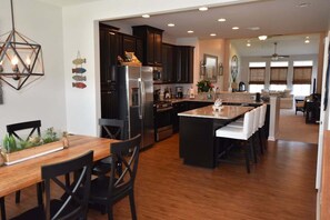 A modern kitchen with dark cabinetry, stainless steel appliances, and a central island with seating.