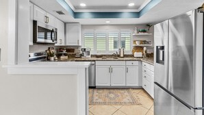 A modern kitchen with white cabinetry, stainless steel appliances, and a skylight. - 6703 Midnight Pass RD · Siesta Key Condo, Heated Pool, Newly Renovated (Siesta Key)