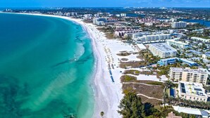 An aerial view of a coastal city with a wide beach, beachfront hotels, and dense urban development.