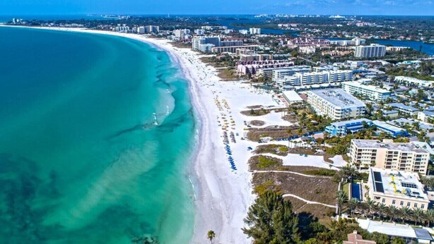 An aerial view of a coastal city with a wide beach, beachfront hotels, and dense urban development. - 6703 Midnight Pass RD · Siesta Key Condo, Heated Pool, Newly Renovated (Siesta Key)