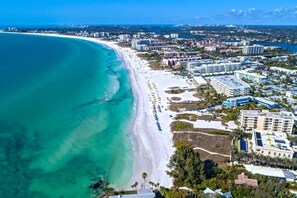 An aerial view of a coastal city with a wide beach, beachfront hotels, and dense urban development. - 6703 Midnight Pass RD · Siesta Key Condo, Heated Pool, Newly Renovated (Siesta Key)