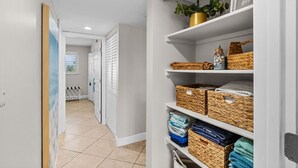 A hallway with storage shelves containing baskets and folded towels. - 6703 Midnight Pass RD · Siesta Key Condo, Heated Pool, Newly Renovated (Siesta Key)